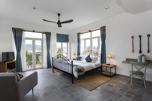 a bedroom with a bed and a couch and windows at Boutique Kampot Hotel in Kampot