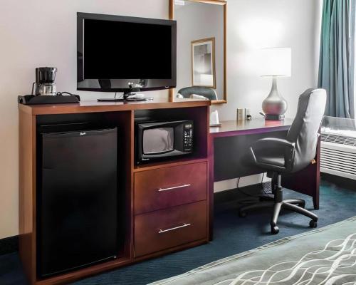 a hotel room with a desk with a television and a chair at Quality Inn Waynesburg - Morrisville in Waynesburg