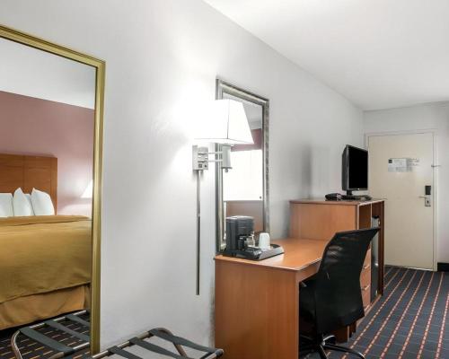 a hotel room with a desk with a bed and a mirror at Quality Inn in Marianna