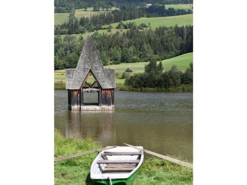 a small house in the middle of a lake with a boat at Holiday apartment Haus Frank in Nassereith