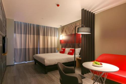 a hotel room with a bed and a red couch at ibis xian North Second Ring Weiyang Rd Hotel in Xi'an