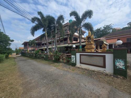 a building with palm trees on the side of a road at Phaiboon Hotel & Resort in Pak Chong