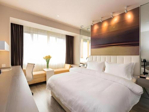 a bedroom with a large white bed and a window at Jinjiang Metropolo Shanghai Xujiahui Nanhuating Hotel in Shanghai