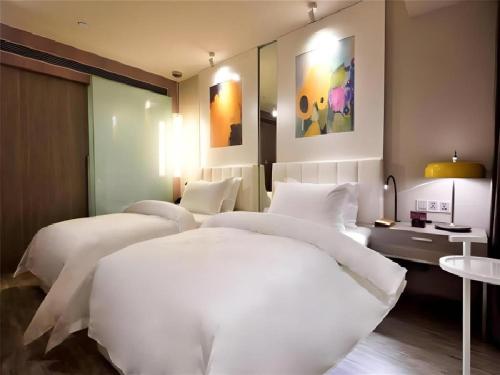 two beds in a hotel room with white sheets at Jinjiang Metropolo Shanghai Xujiahui Nanhuating Hotel in Shanghai