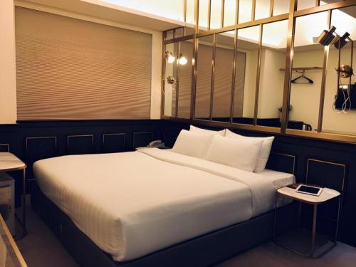a bedroom with a large white bed with a table at King's Hotel in Hong Kong