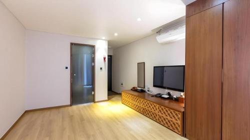 a living room with a television and a wooden entertainment center at Hotel One Byeonsan in Buan