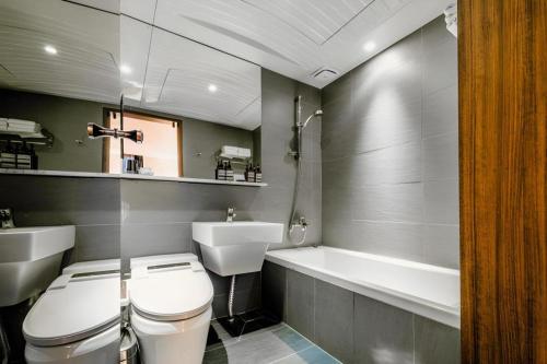 a bathroom with a toilet and a sink and a tub at Hotel One Byeonsan in Buan