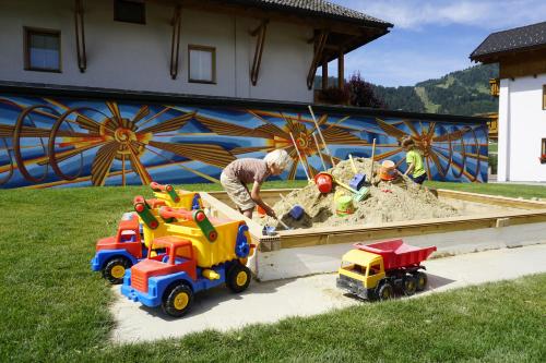 a man playing with toys in a sandbox at Apart-Hotel Dreisonnenhof in Fiss
