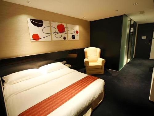 a hotel room with a bed and a chair at Noble Park Hotel in Hong Kong
