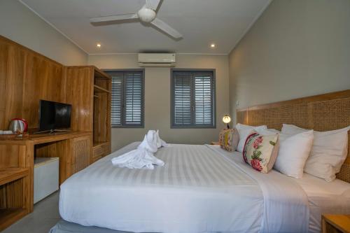 a bedroom with a large white bed and a television at The Peacock Inn in Ubud
