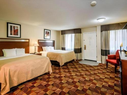 a hotel room with two beds and a red chair at Quality Inn Redding near I-5 in Redding