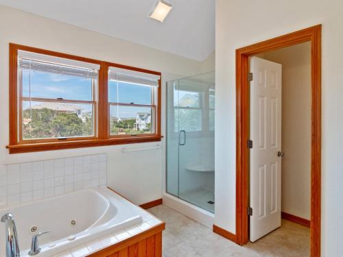 a bathroom with a tub and a glass shower at 2072 - Laughing Duck in Duck