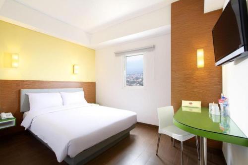a bedroom with a white bed and a green desk at Amaris Hotel Pakuan Bogor in Bogor