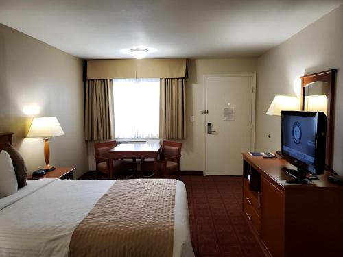 a hotel room with a bed and a flat screen tv at Airport Inn in Boise
