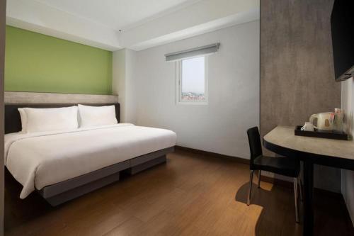 a bedroom with a bed and a desk with a desk at Amaris Hotel Pakuan Bogor in Bogor