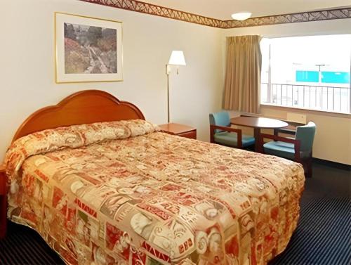 a hotel room with a bed and a table and chairs at Econo Lodge Airport in Norfolk