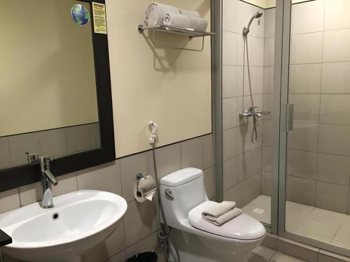 a bathroom with a toilet and a sink and a shower at Baguio Burnham Suites Hotel in Baguio