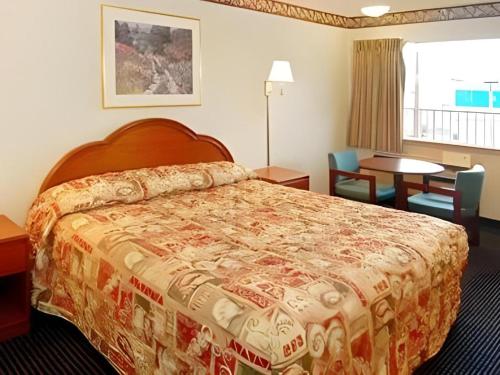 a hotel room with a bed and a table and chairs at Econo Lodge Airport in Norfolk