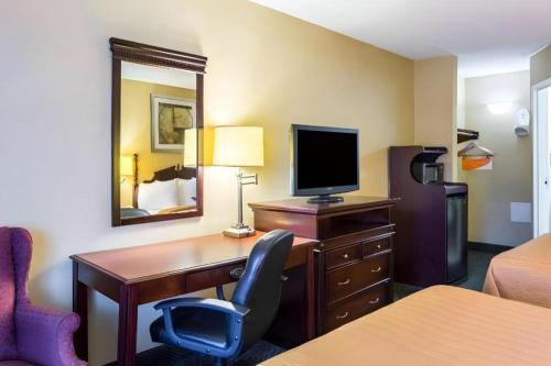 a hotel room with a desk with a computer and a bed at Quality Inn in Manassas