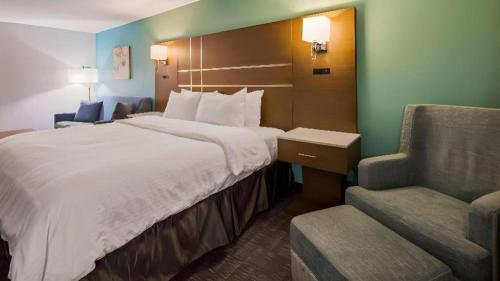 a hotel room with a large bed and a chair at Best Western Galt Inn in Galt