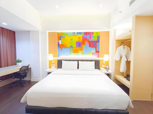 a bedroom with a large white bed and a desk at Brits Hotel Karawang in Karawang