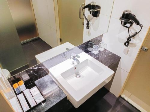 a bathroom with a white sink and a mirror at Brits Hotel Karawang in Karawang