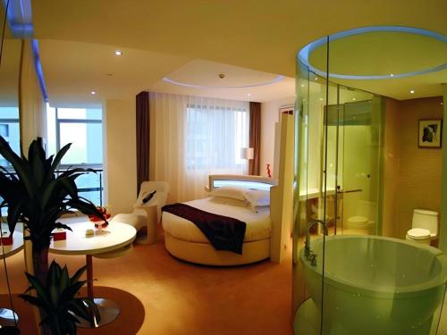 a bedroom with a bed and a bathroom with a tub at Ramada Plaza by Wyndham Hangzhou Riverside in Hangzhou