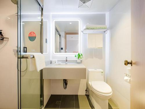a bathroom with a sink and a toilet and a mirror at GreenTree Inn Shanghai Jingan Railway Station Xinzha Road Business Hotel in Shanghai