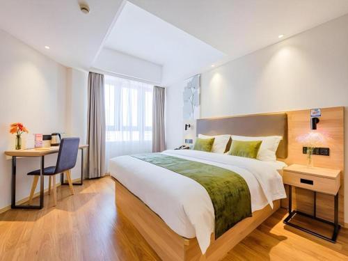 a hotel room with a large bed and a desk at GreenTree Inn Shanghai Jingan Railway Station Xinzha Road Business Hotel in Shanghai