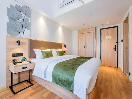 a bedroom with a large white bed and a desk at GreenTree Inn Shanghai Jingan Railway Station Xinzha Road Business Hotel in Shanghai