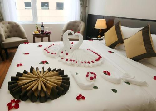 two white swans sitting on a bed with flowers on it at Lenid Hotel Tho Nhuom in Hanoi