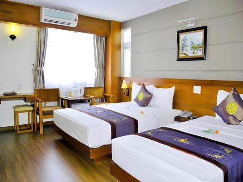 a hotel room with two beds and a desk at Barcelona Hotel Nha Trang in Nha Trang