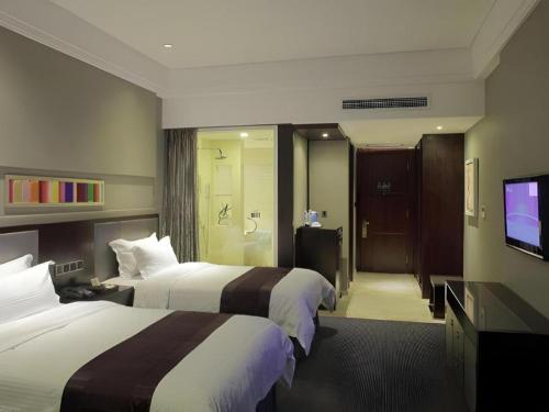 a hotel room with two beds and a flat screen tv at New Century Manju Hotel Shanghai New International Expo Center in Shanghai