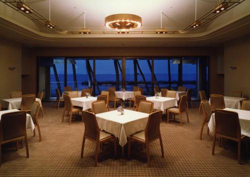 a dining room with tables and chairs and windows at Kasuitei in Yonago