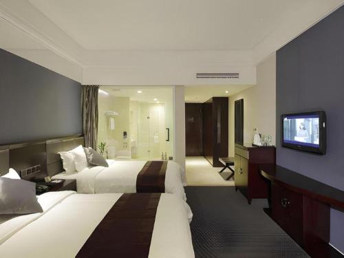 a hotel room with two beds and a flat screen tv at New Century Manju Hotel Shanghai New International Expo Center in Shanghai