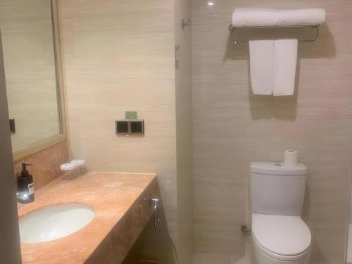 a bathroom with a white toilet and a sink at New Century Manju Hotel Shanghai New International Expo Center in Shanghai