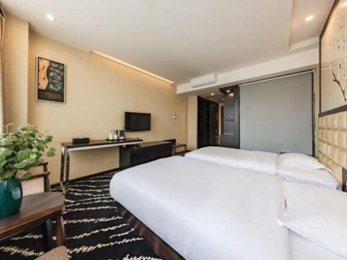 a bedroom with a large white bed and a desk at Kunming Long Way Hotel in Kunming
