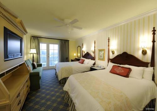 a hotel room with two beds and a flat screen tv at Disney's Boardwalk Inn in Orlando