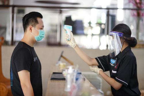 two people wearing masks and gloves holding up a device at Raffleshom Hotel in Bandung