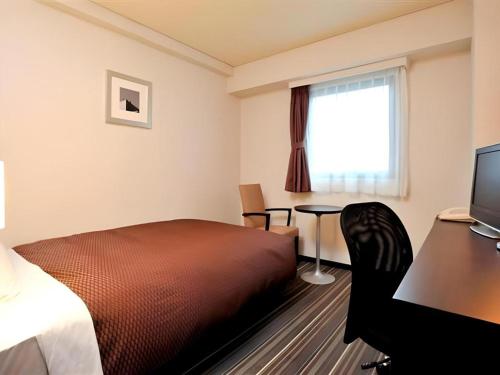 a hotel room with a bed and a desk and a window at Daini Fuji Hotel in Nagoya
