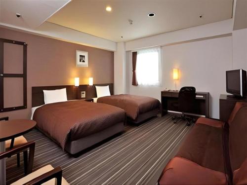 a hotel room with two beds and a television at Daini Fuji Hotel in Nagoya