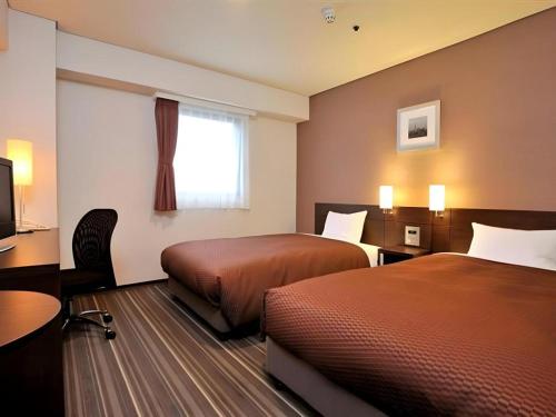 a hotel room with two beds and a television at Daini Fuji Hotel in Nagoya