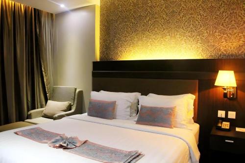 a hotel room with a large bed and a chair at The Belagri Hotel and Convention in Sorong