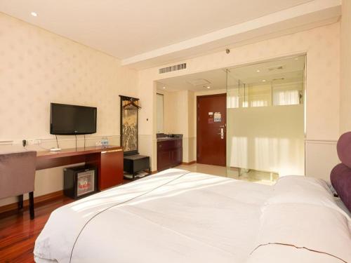 a bedroom with a large white bed and a tv at Yiwu Baiheng Hotel in Yiwu