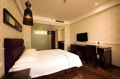 a bedroom with a bed and a desk and a television at Yiwu Baiheng Hotel in Yiwu