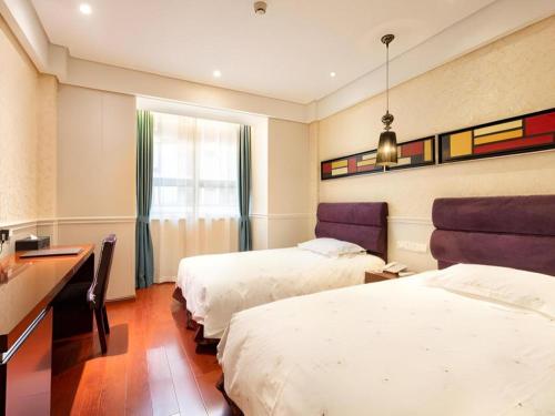 a hotel room with two beds and a desk at Yiwu Baiheng Hotel in Yiwu