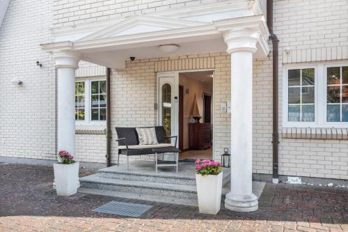 a porch with two white columns and a chair at Traumhaus Whirlpool Sauna Grill in Hamburg