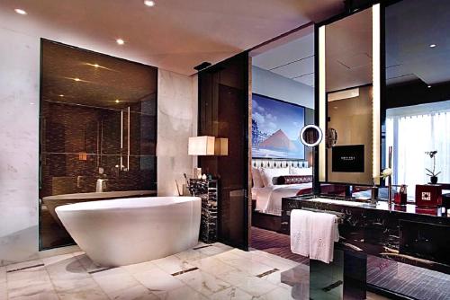 a bathroom with a tub and a large mirror at Sofitel Guangzhou Sunrich - Free Shuttle Bus to Canton Fair Complex & Overseas Buyer Registration Services during Canton Fair Period in Guangzhou