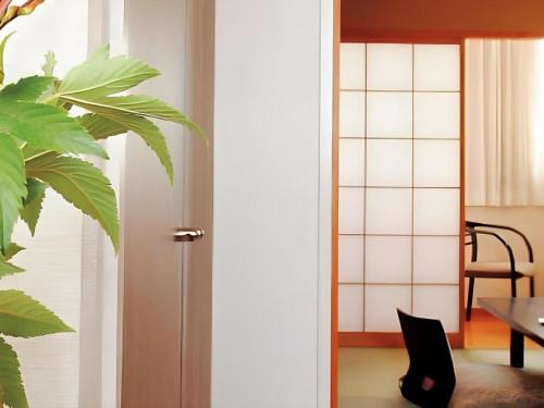 a door leading into a room with a table and a plant at Shirako New Seaside Hotel in Shirako