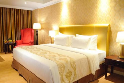 a hotel room with a large bed and a red chair at Adimulia Hotel Medan in Medan